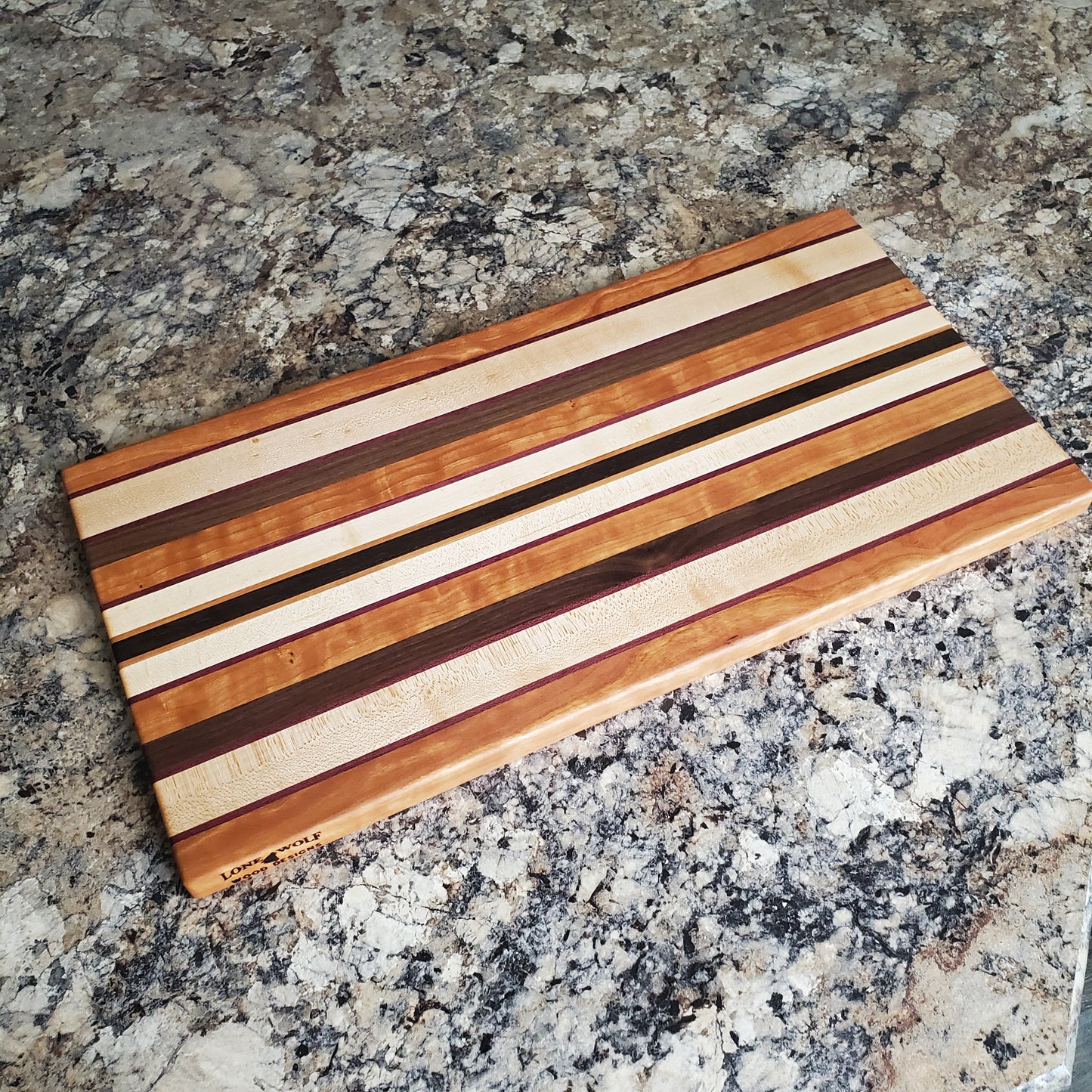 Signature Series Peekaboo cutting board made from maple, walnut, cherry, purple heart, and wenge by Lone Wolf Wood Designs