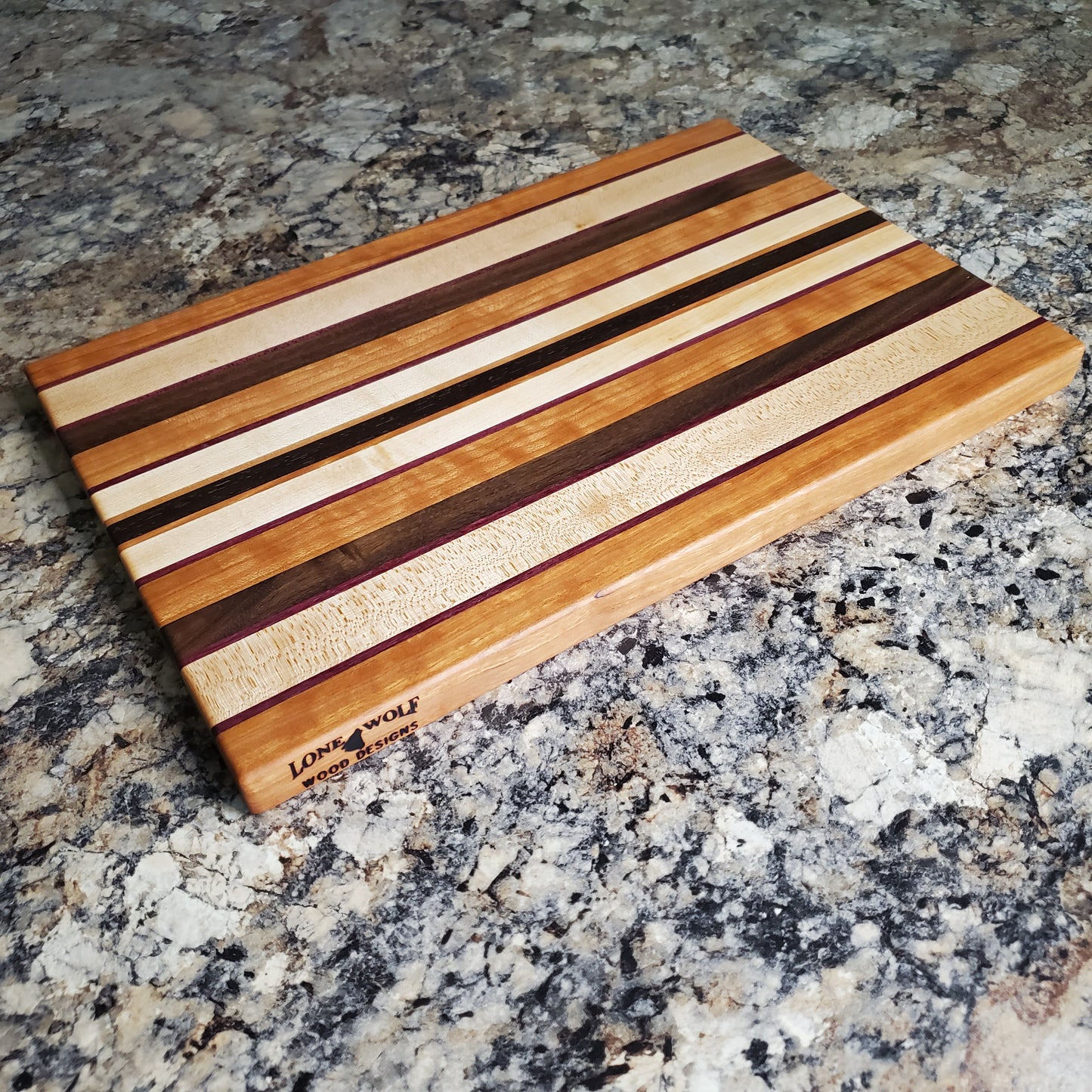 Signature Series Peekaboo cutting board made from maple, walnut, cherry, purple heart, and wenge by Lone Wolf Wood Designs