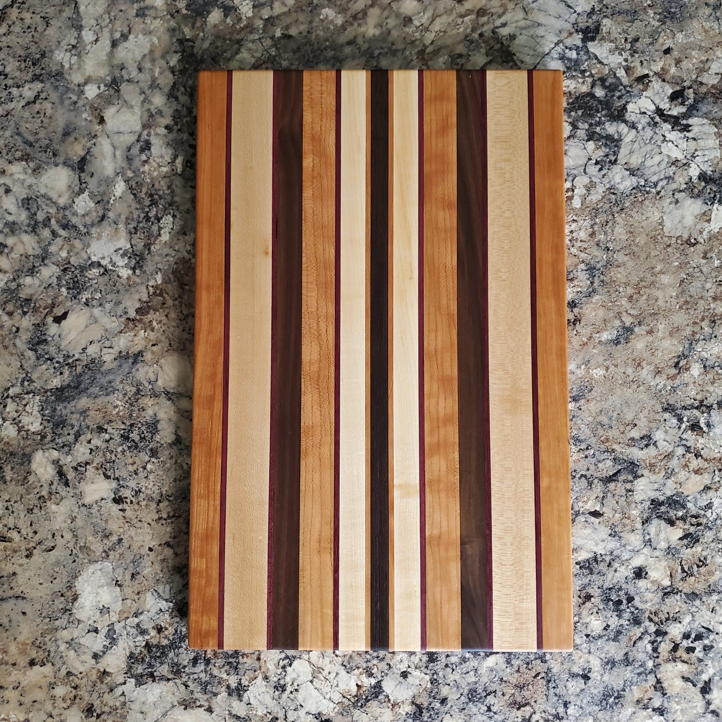 Signature Series Peekaboo cutting board made from maple, walnut, cherry, purple heart, and wenge by Lone Wolf Wood Designs