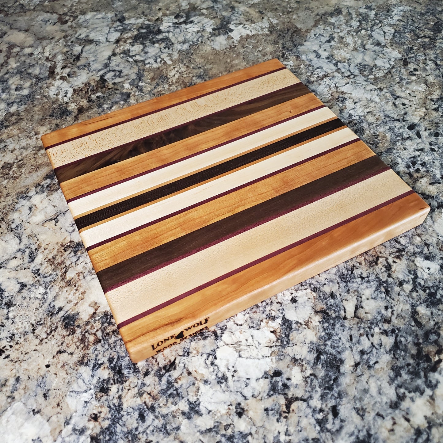 Signature Series Peekaboo cutting board made from maple, walnut, cherry, purple heart, and wenge by Lone Wolf Wood Designs