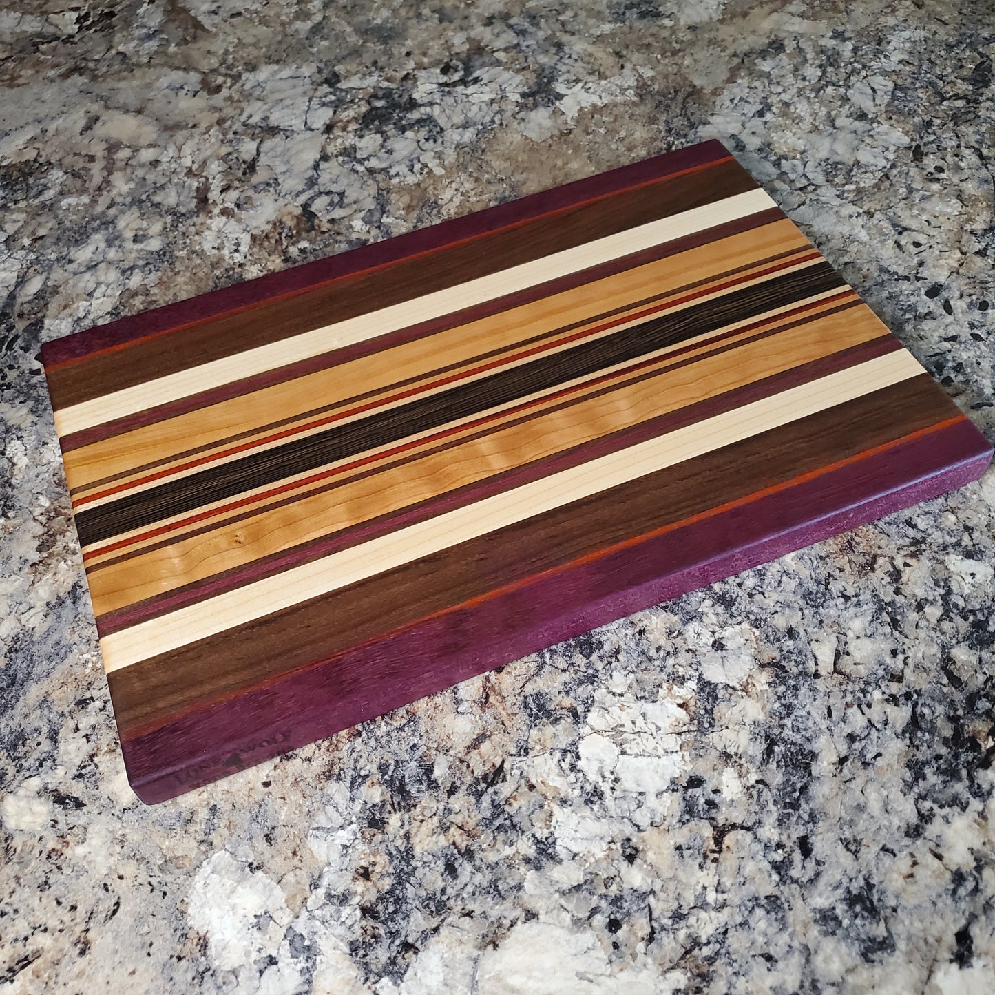 Signature Series Royalty cutting board made from maple, walnut, cherry, padauk, purple heart, and wenge by Lone Wolf Wood Designs