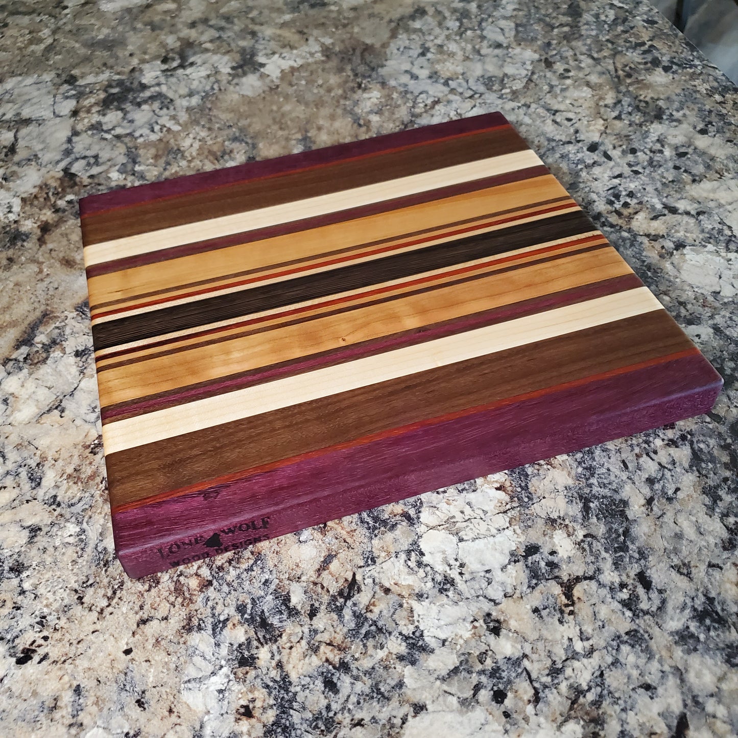 Signature Series Royalty cutting board made from maple, walnut, cherry, padauk, purple heart, and wenge by Lone Wolf Wood Designs