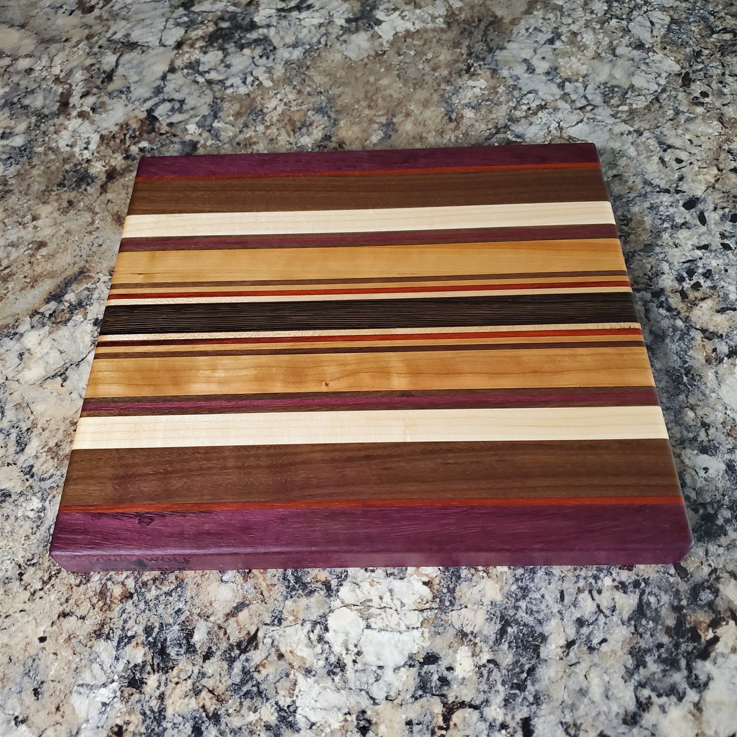 Signature Series Royalty cutting board made from maple, walnut, cherry, padauk, purple heart, and wenge by Lone Wolf Wood Designs