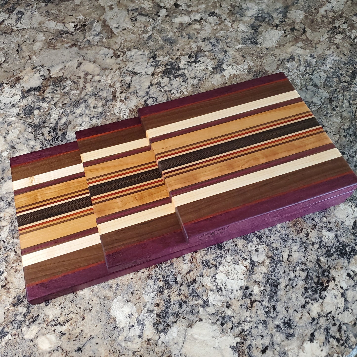 Signature Series Royalty cutting board made from maple, walnut, cherry, padauk, purple heart, and wenge by Lone Wolf Wood Designs