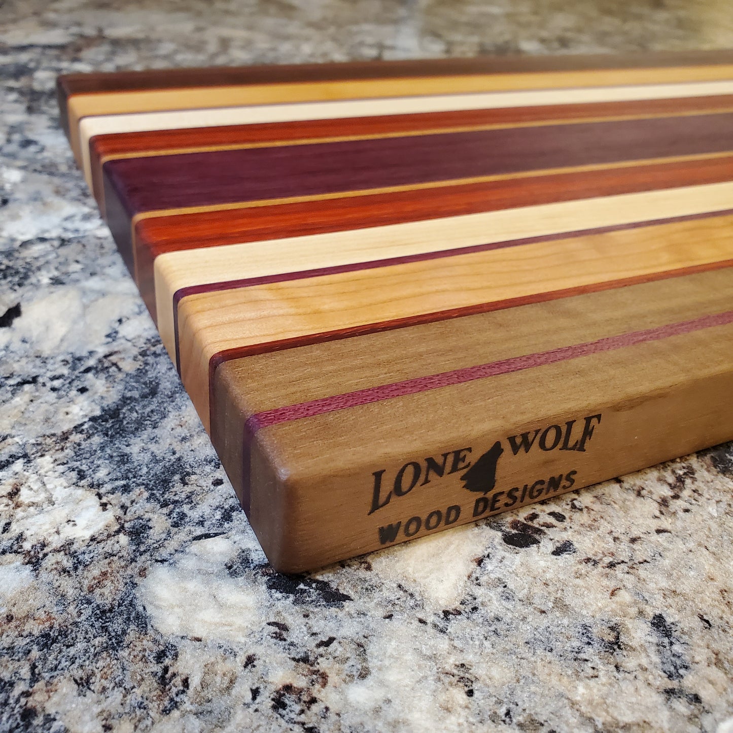 Signature Series Sunset cutting board made from walnut, cherry, maple, purple heart, and padauk by Lone Wolf Wood Designs