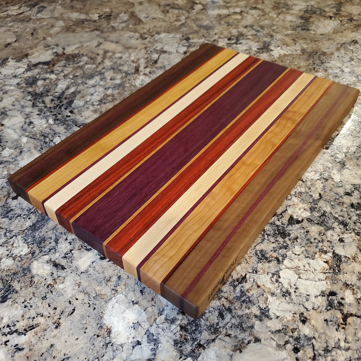 Signature Series Sunset cutting board made from walnut, cherry, maple, purple heart, and padauk by Lone Wolf Wood Designs