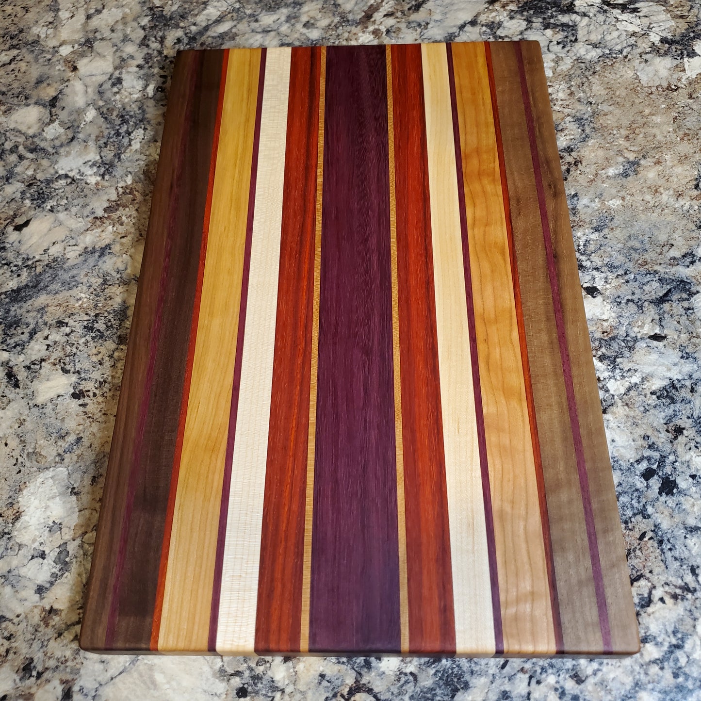 Signature Series Sunset cutting board made from walnut, cherry, maple, purple heart, and padauk by Lone Wolf Wood Designs