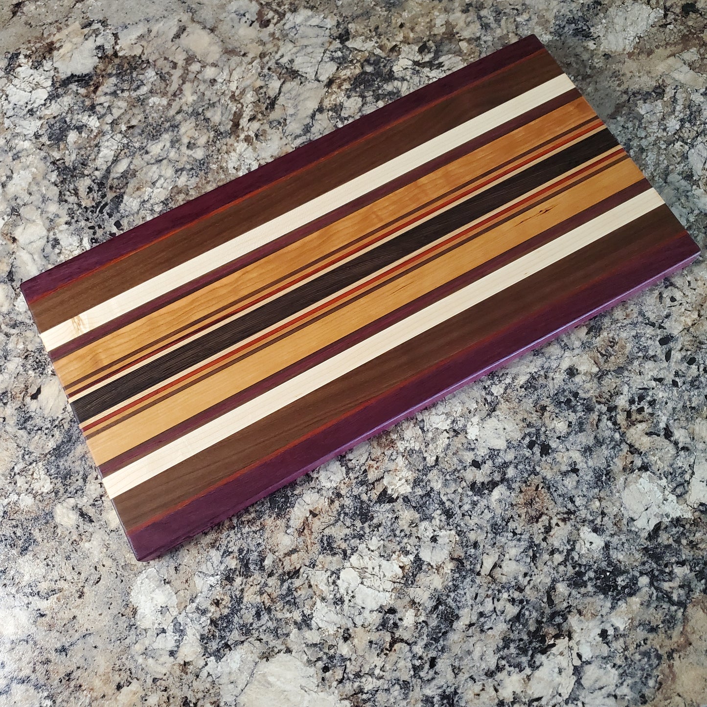 Signature Series Royalty cutting board made from maple, walnut, cherry, padauk, purple heart, and wenge by Lone Wolf Wood Designs