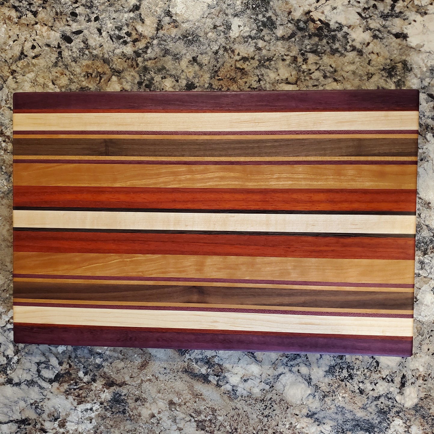 Signature Series Tiger Lily cutting board made from walnut, cherry, maple, purple heart, wenge, and padauk by Lone Wolf Wood Designs