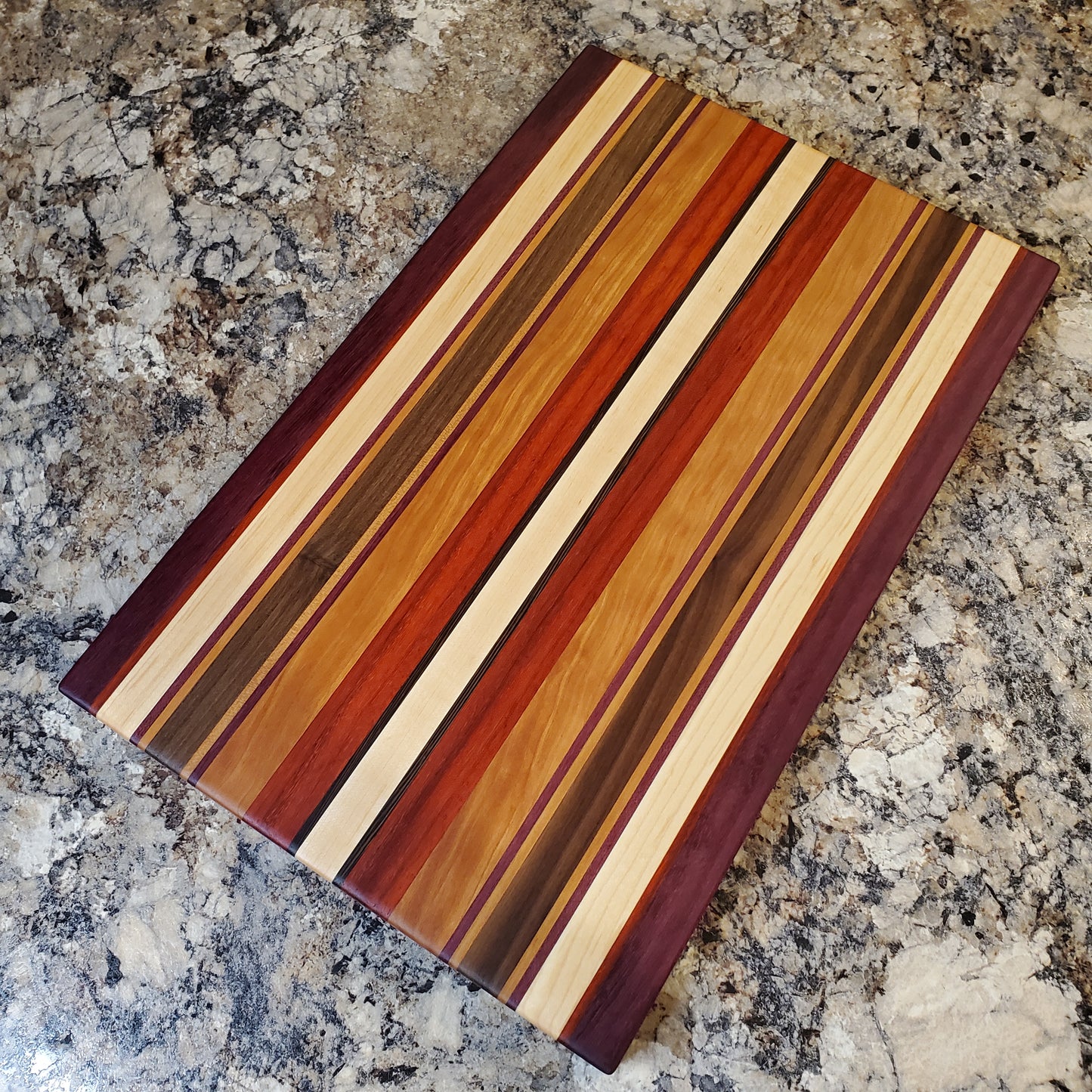 Signature Series Tiger Lily cutting board made from walnut, cherry, maple, purple heart, wenge, and padauk by Lone Wolf Wood Designs