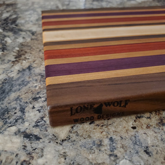 Signature Series Wild Plum cutting board made from walnut, cherry, maple, purple heart, and padauk by Lone Wolf Wood Designs