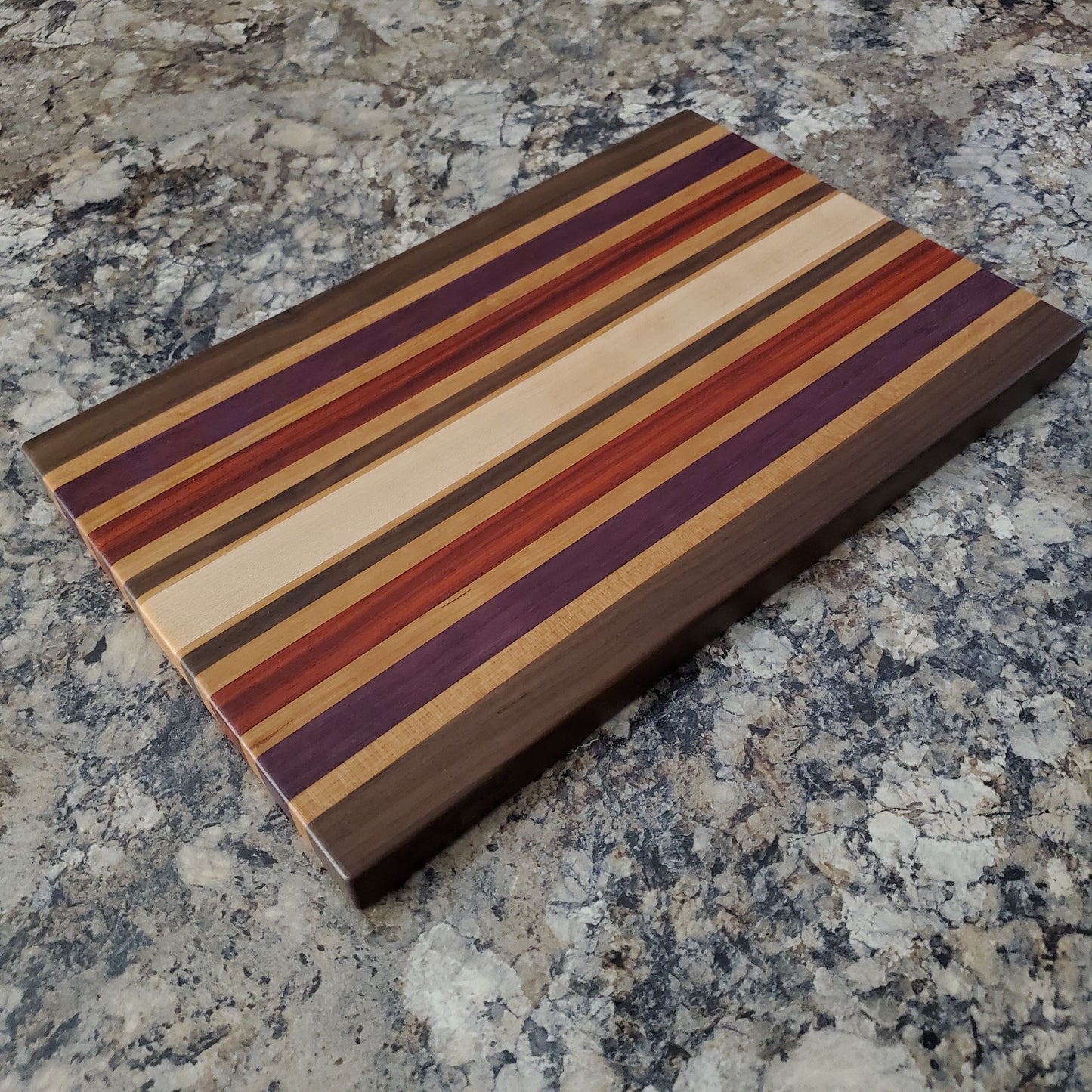 Signature Series Wild Plum cutting board made from walnut, cherry, maple, purple heart, and padauk by Lone Wolf Wood Designs