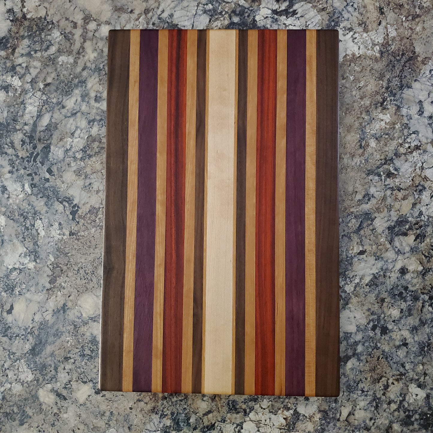 Signature Series Wild Plum cutting board made from walnut, cherry, maple, purple heart, and padauk by Lone Wolf Wood Designs