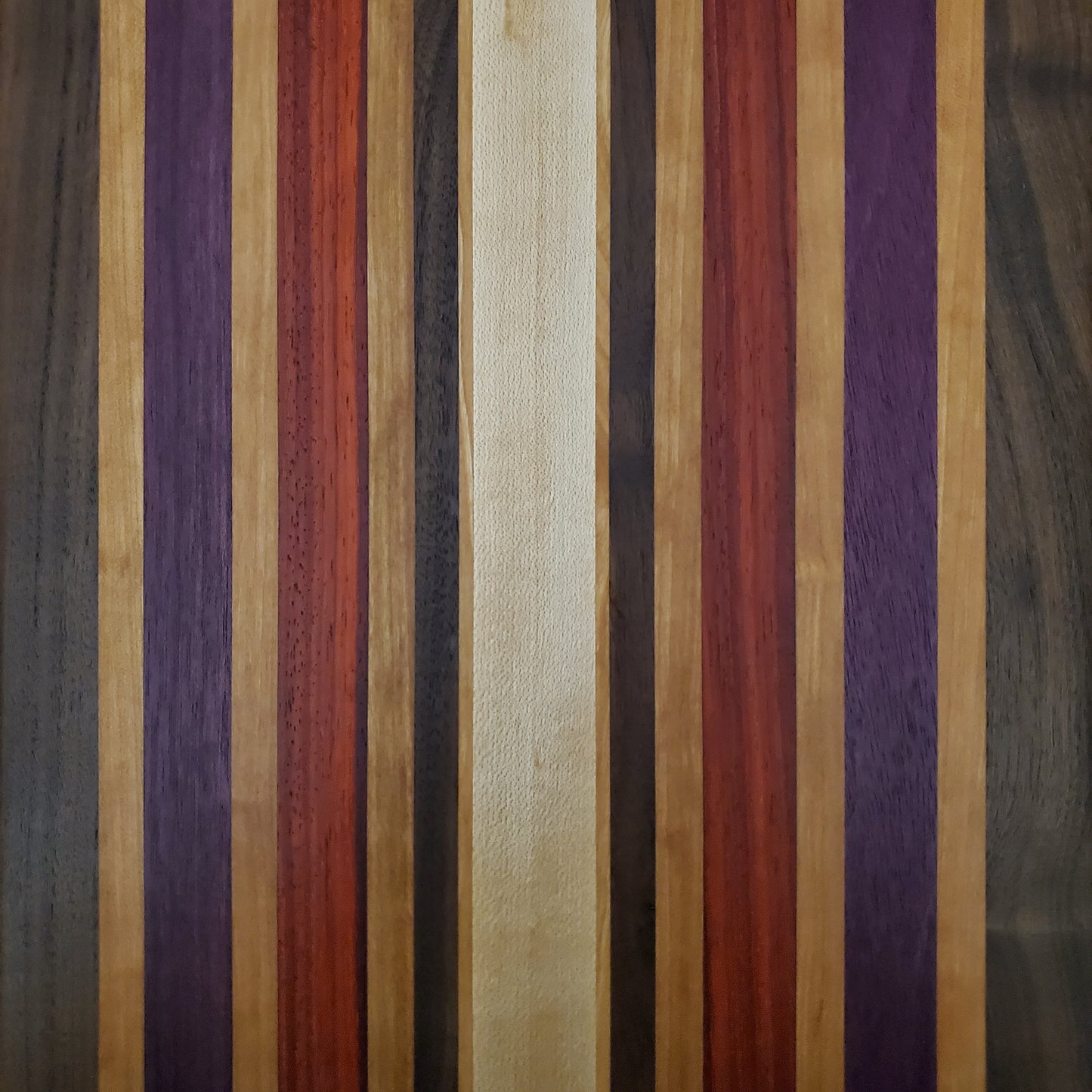 Signature Series Wild Plum cutting board made from walnut, cherry, maple, purple heart, and padauk by Lone Wolf Wood Designs