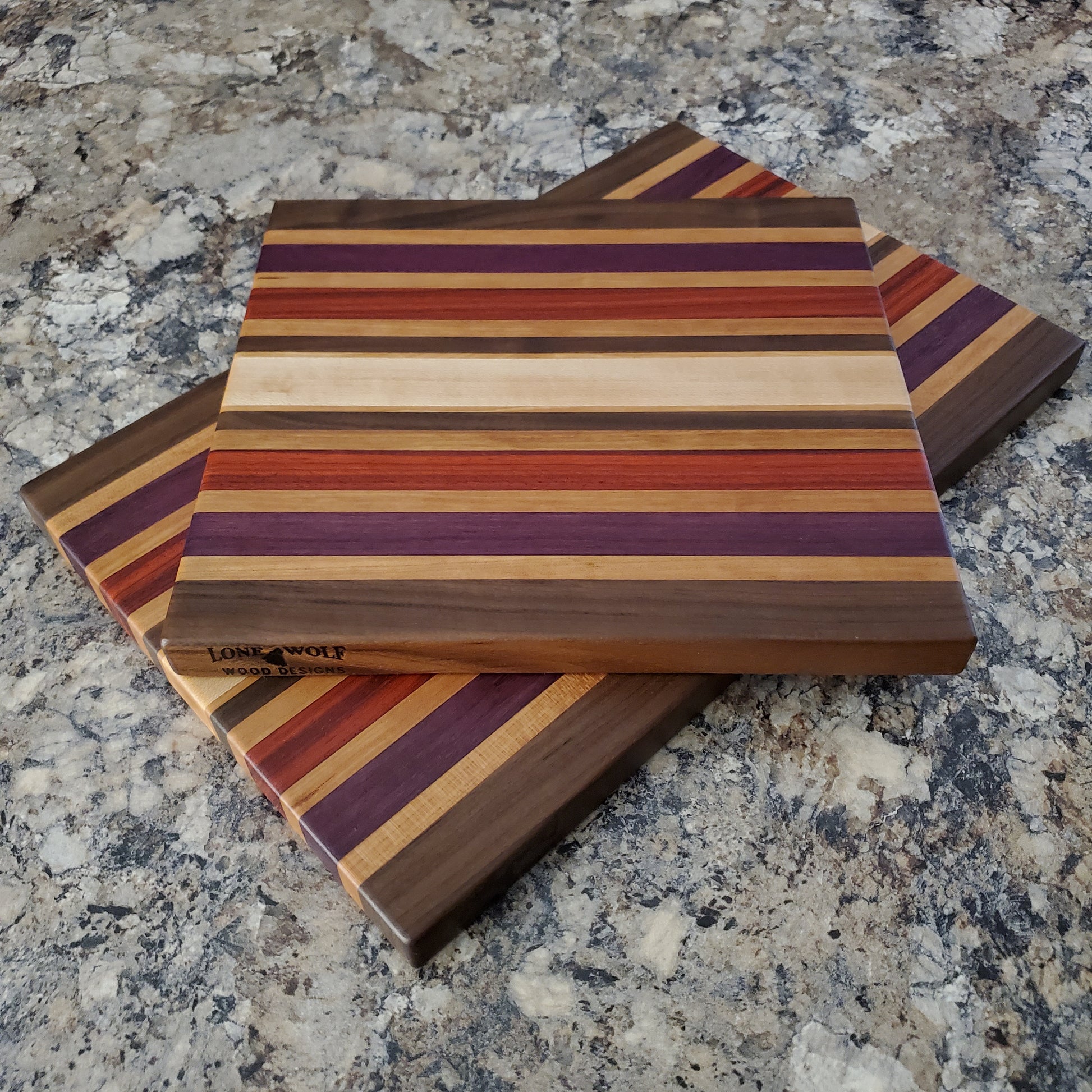 Signature Series Wild Plum cutting board made from walnut, cherry, maple, purple heart, and padauk by Lone Wolf Wood Designs