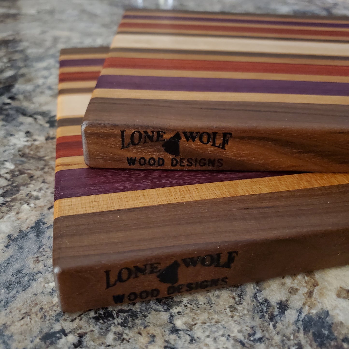 Signature Series Wild Plum cutting board made from walnut, cherry, maple, purple heart, and padauk by Lone Wolf Wood Designs