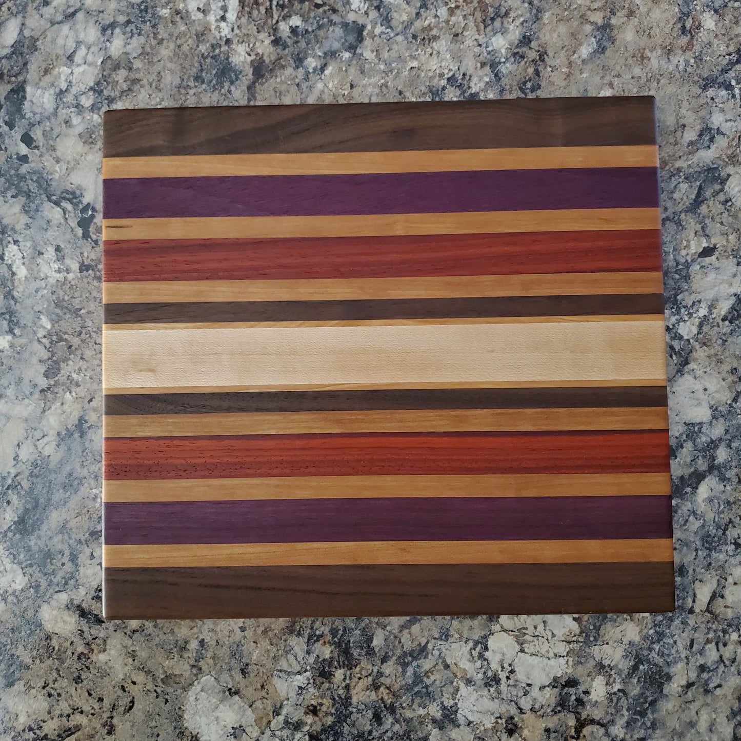 Signature Series Wild Plum cutting board made from walnut, cherry, maple, purple heart, and padauk by Lone Wolf Wood Designs